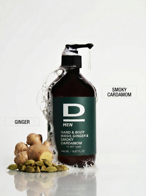 Braune Flasche mit grünem Etikett und schwarzem Pumpverschluss, umgeben von Ingwerstücken und Kardamomkapseln, mit Schaum auf der Flasche