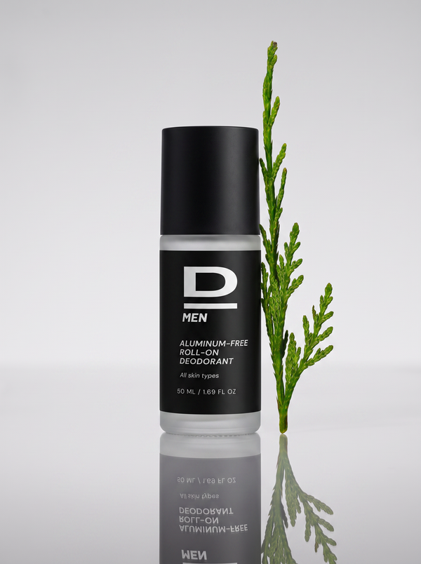 Roll-on-Deodorantflasche mit schwarzem Deckel und schwarzem Etikett vor einem grünen Zweig