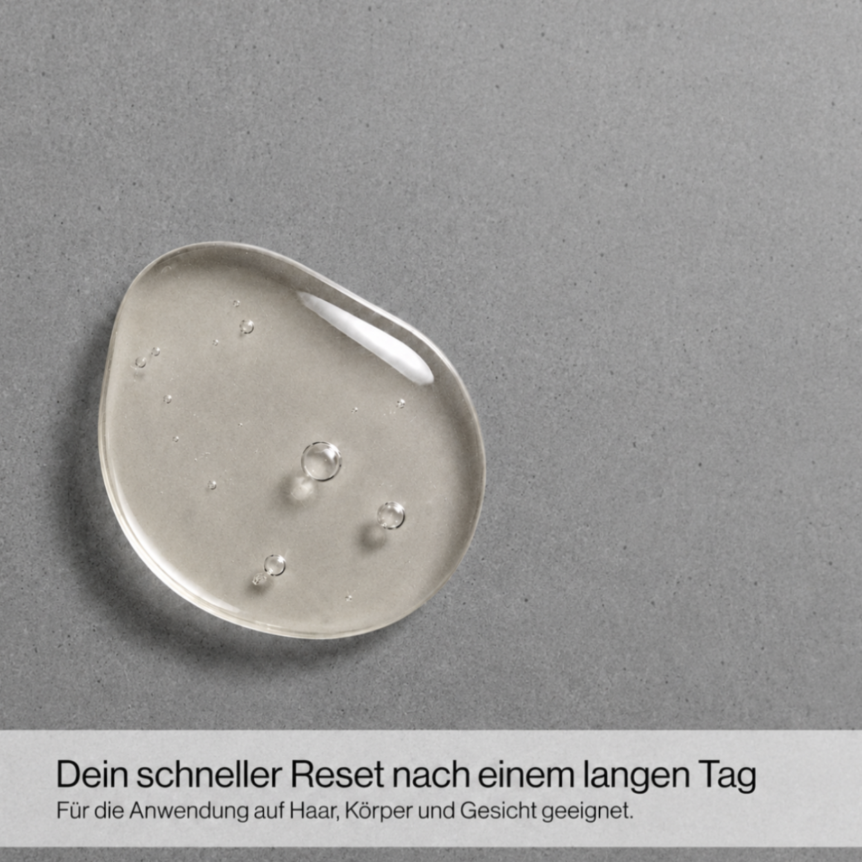 Nahaufnahme eines transparenten Gelkleckses auf grauem Untergrund mit Text 'Dein schneller Reset nach einem langen Tag Für die Anwendung auf Haar, Körper und Gesicht geeignet'