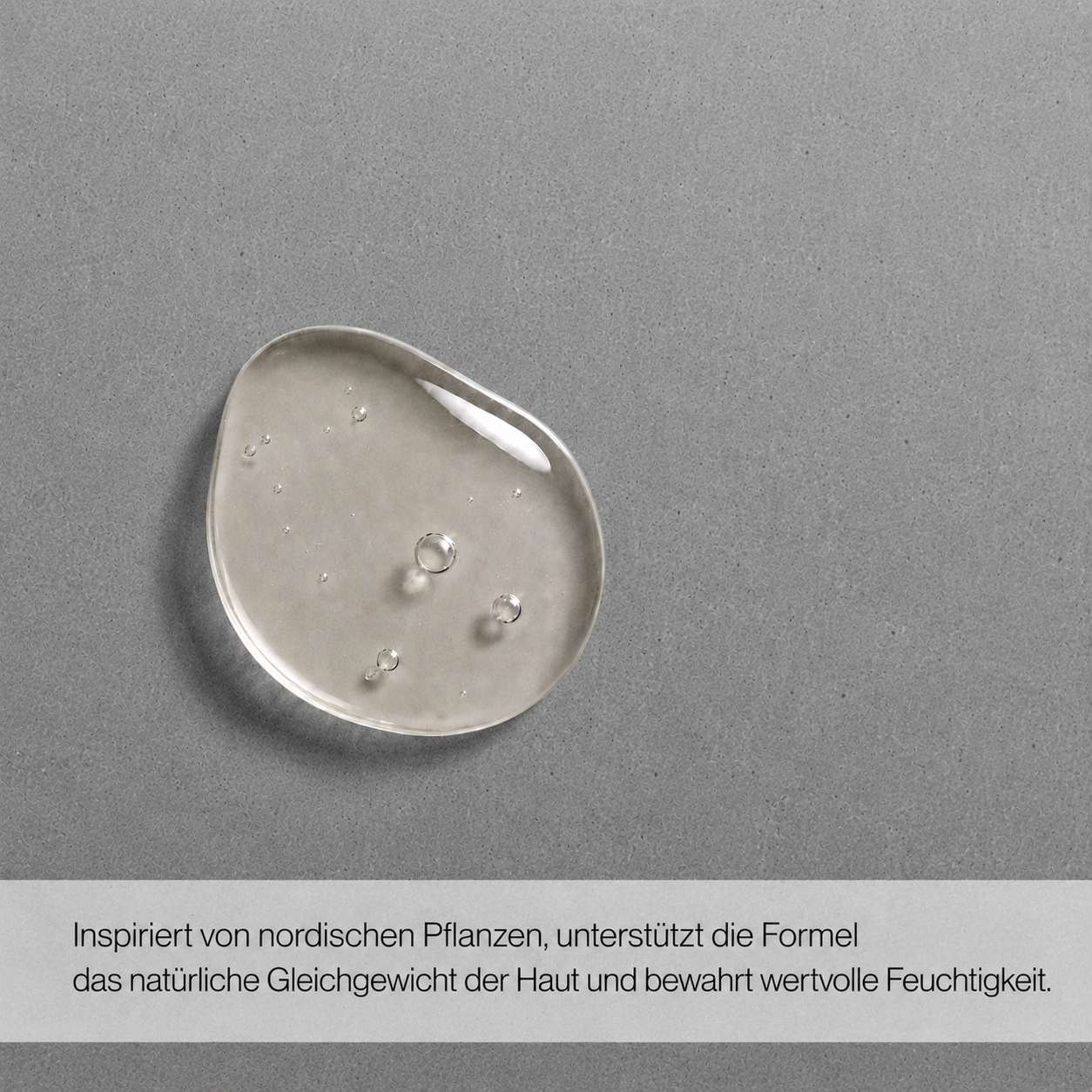 Nahaufnahme eines transparenten Gelkleckses auf grauem Untergrund mit Text 'Dein schneller Reset nach einem langen Tag Für die Anwendung auf Haar, Körper und Gesicht geeignet'