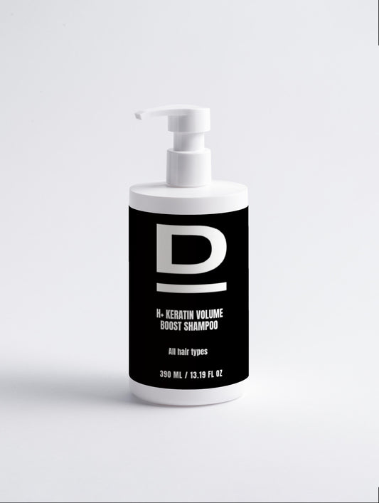 Weißer Shampoo-Spender mit schwarzem Etikett und der Aufschrift 'D H-KERATIN VOLUME BOOST SHAMPOO All hair types 390 ML / 13.19 FL OZ'.