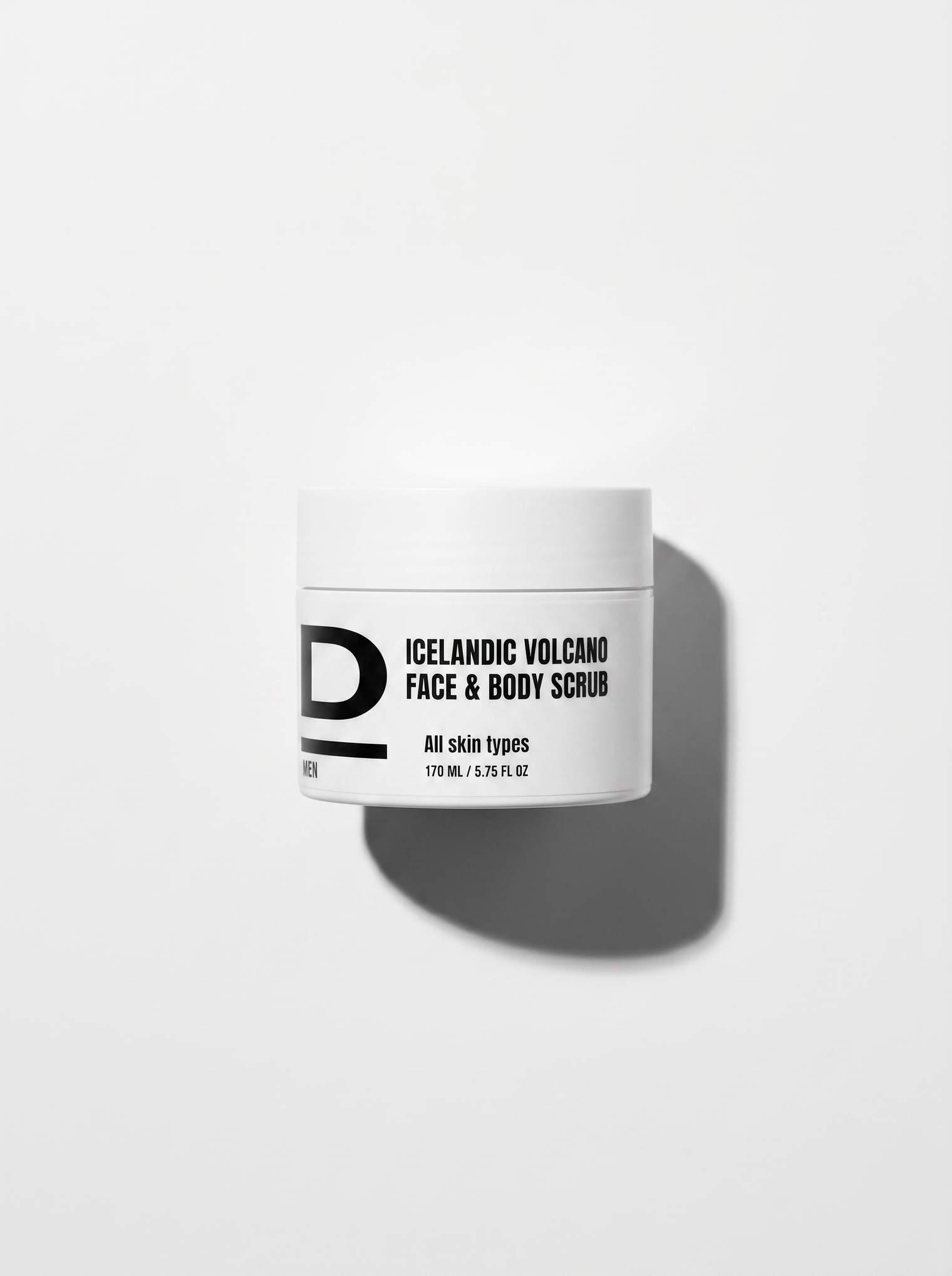 Weißer Tiegel mit schwarzer Aufschrift "ICELANDIC VOLCANO FACE & BODY SCRUB" und Schatten auf weißem Hintergrund