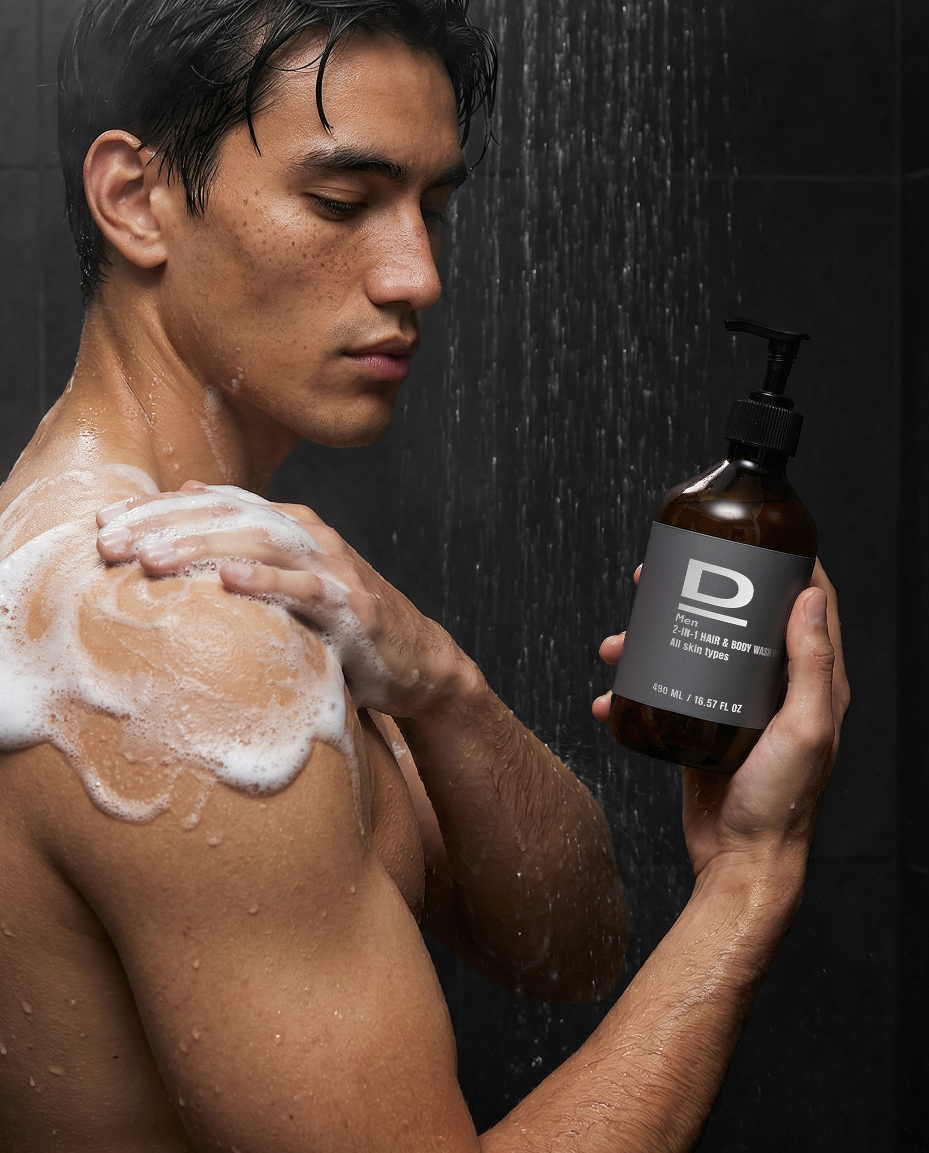 Mann im Duschbereich mit schäumendem Shampoo, Flasche 2-in-1 Duschgel für Haar und Körper im Vordergrund.