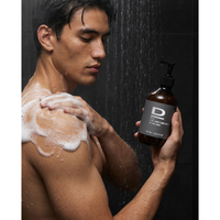 Mann im Duschbereich mit schäumendem Shampoo, Flasche 2-in-1 Duschgel für Haar und Körper im Vordergrund.