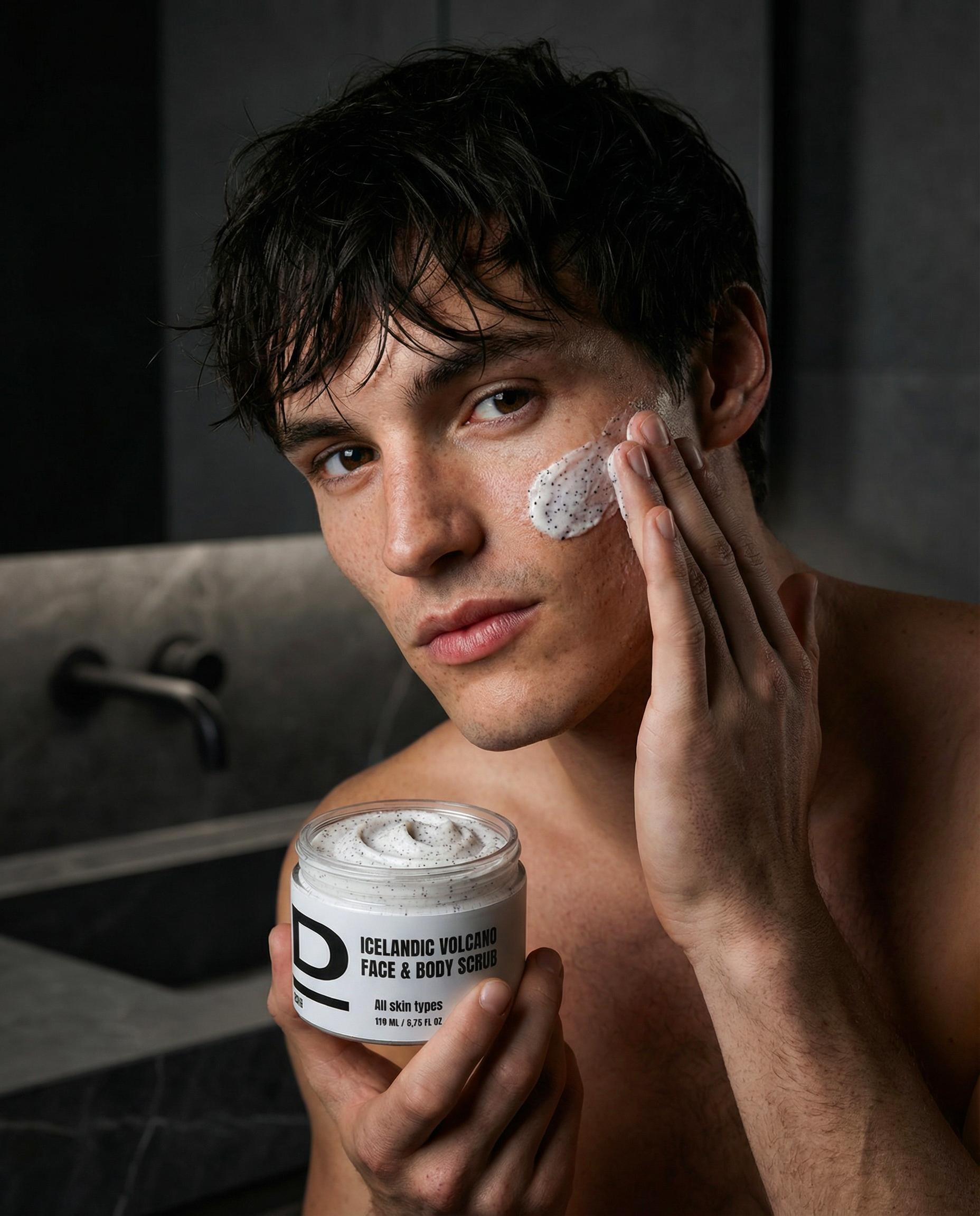Mann trägt den Icelandic Volcano Face & Body Scrub auf sein Gesicht auf, zeigt die Produktverpackung.