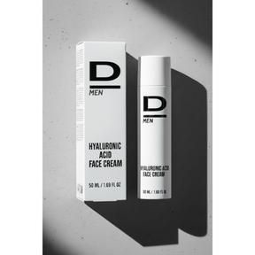 Verpackung und Flasche einer Gesichtscreme mit der Aufschrift 'D MEN HYALURONIC ACID FACE CREAM 50 ML / 1.69 FL OZ' auf hellem Untergrund mit Schatten