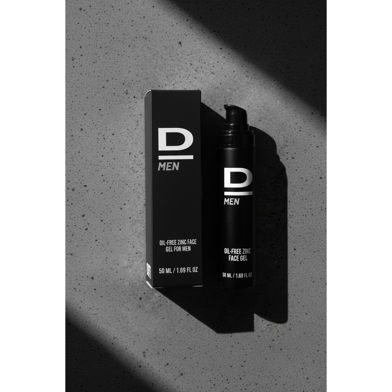 Aufrecht stehende schwarze Verpackung und Flasche mit weißer Aufschrift 'D MEN OIL-FREE ZINC FACE GEL FOR MEN 50 ML / 1.69 FL OZ' auf grauem Untergrund mit Schatten