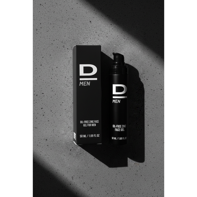 Aufrecht stehende schwarze Verpackung und Flasche mit weißer Aufschrift 'D MEN OIL-FREE ZINC FACE GEL FOR MEN 50 ML / 1.69 FL OZ' auf grauem Untergrund mit Schatten
