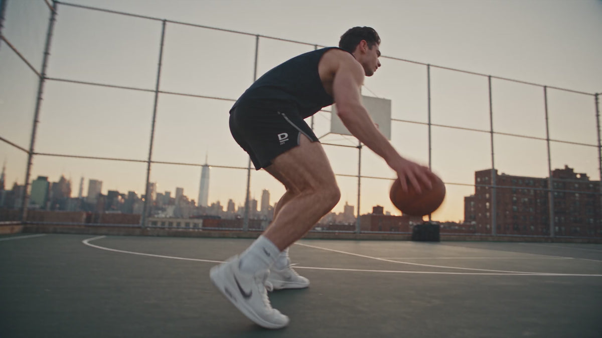 Werbevideo für Deportes Men Skincare: Ein junger Mann in schwarzem Tanktop spielt bei Sonnenuntergang Basketball auf einem Court mit Skyline im Hintergrund. Nach dem Spiel setzt er sich neben seine Sporttasche, nimmt eine schwarze Flasche mit „D Men”-Logo heraus, trägt das Oil-Free Face Gel mit geschlossenen Augen auf sein Gesicht auf und hält die Flasche am Ende direkt in die Kamera.