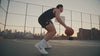 Werbevideo für Deportes Men Skincare: Ein junger Mann in schwarzem Tanktop spielt bei Sonnenuntergang Basketball auf einem Court mit Skyline im Hintergrund. Nach dem Spiel setzt er sich neben seine Sporttasche, nimmt eine schwarze Flasche mit „D Men”-Logo heraus, trägt das Oil-Free Face Gel mit geschlossenen Augen auf sein Gesicht auf und hält die Flasche am Ende direkt in die Kamera.