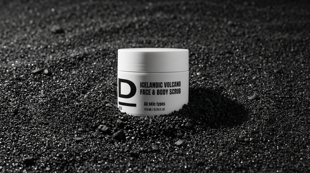 Weißer Tiegel mit schwarzer Aufschrift 'ICELANDIC VOLCANO FACE & BODY SCRUB' steht auf schwarzem, körnigem Vulkanboden