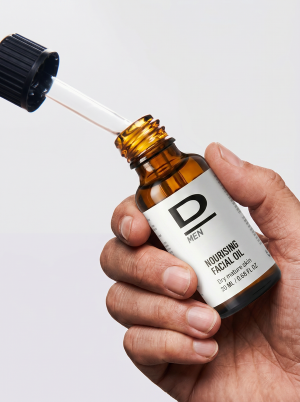 Hand hält eine braune Glasflasche mit Pipette und Aufschrift 'D MEN NOURISHING FACIAL OIL'